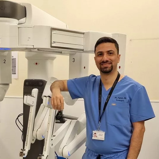 Surgeon Ayman Ali in front of a medical robot