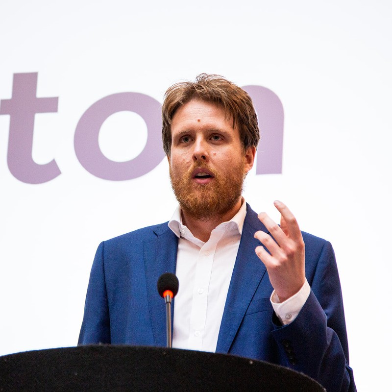 Dr Alasdair Price, CEO and co-founder of Siloton, standing at a lectern with a microphone in front of him.