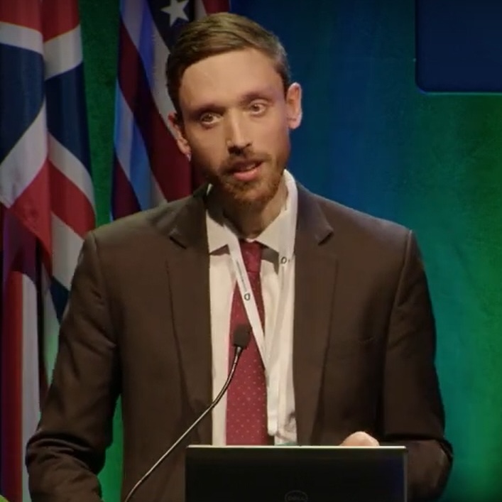 Tom Newby, speaking at a lectern.
