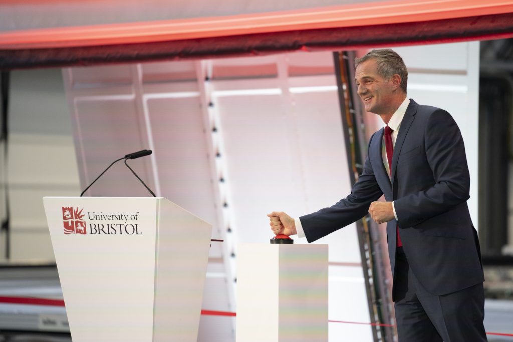Peter Kyle, Secretary of State for Science, Innovation and Technology, standing at a stadium and pushing a large red switch.