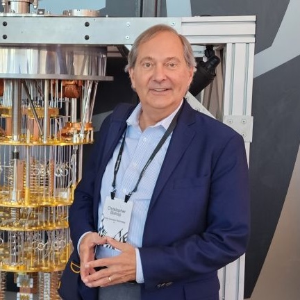 A headshot of Christopher Bishop, in front of quantum computing equipment.