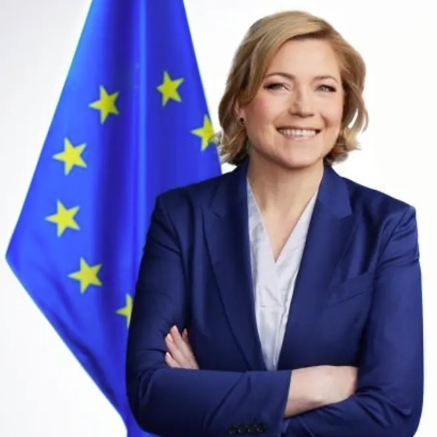 A headshot of Henna Virkkunen, standing in front of an EU flag.