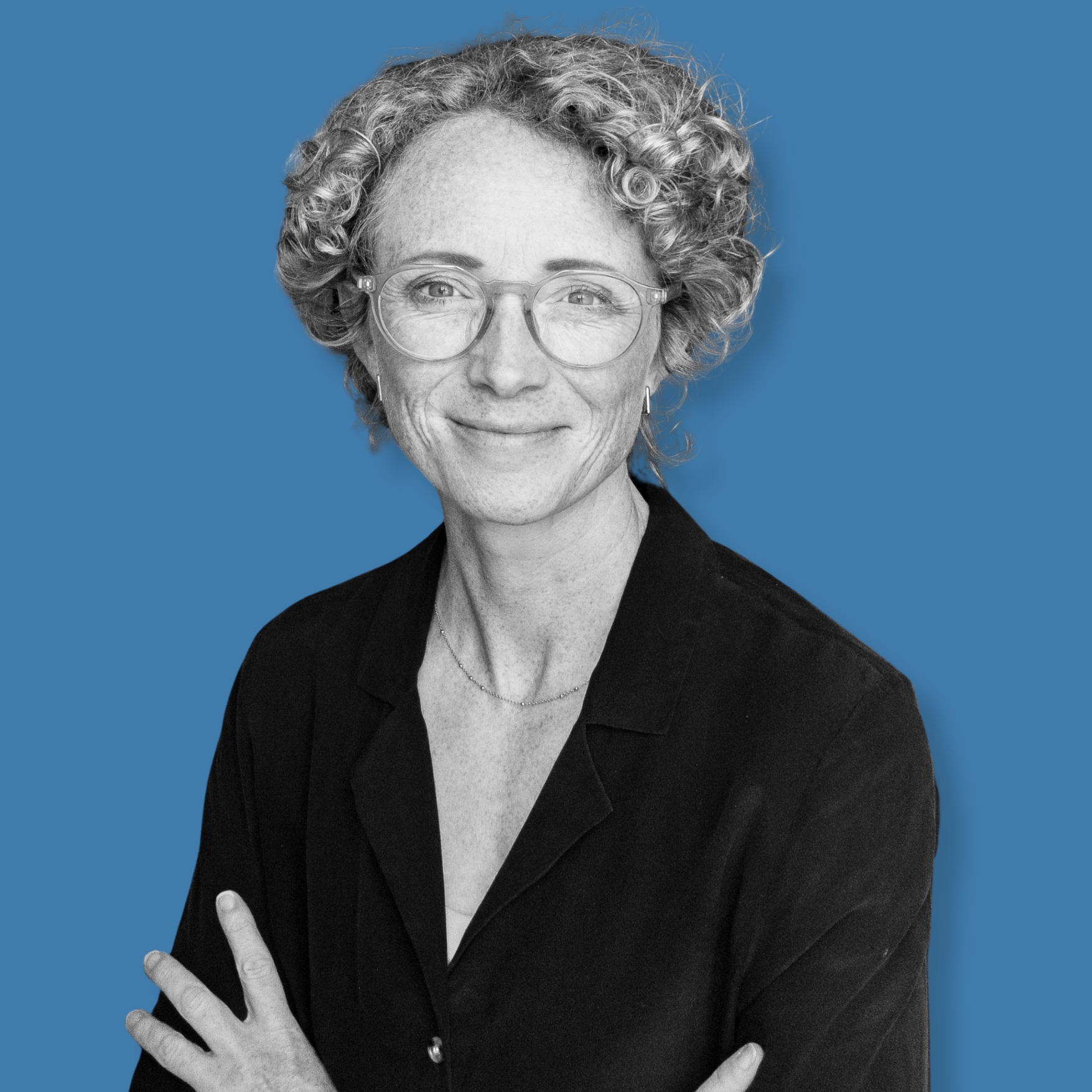 A headshot of Lisa Matthews, in black and white on a blue background.