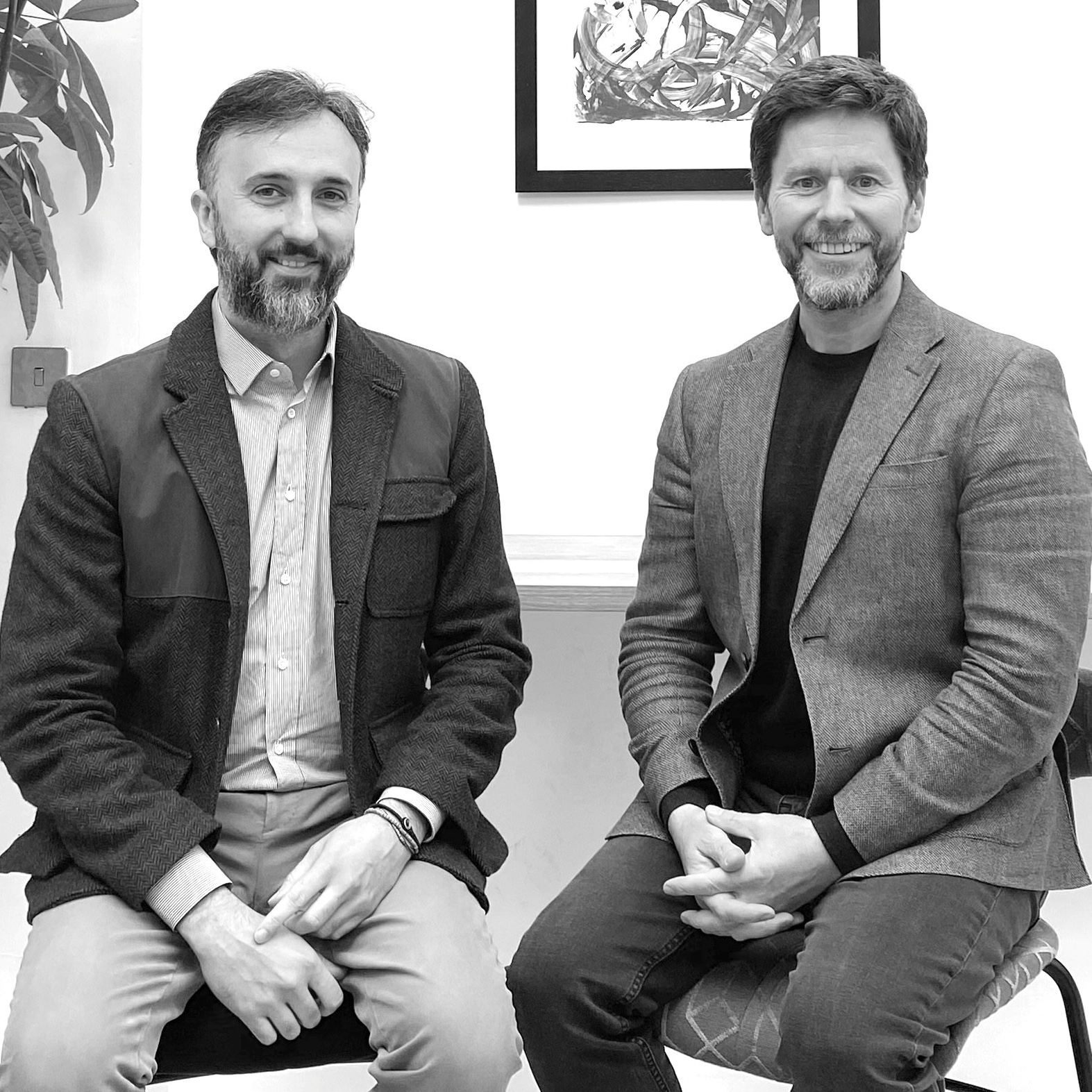 A black and white photograph of two men sitting on chairs. They are the co-founders of Duality Quantum Photonics.