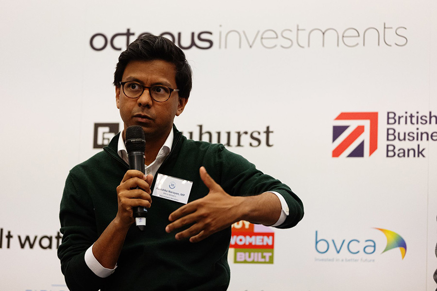 AI Minister Kanishka Narayan, holding a microphone at an event.