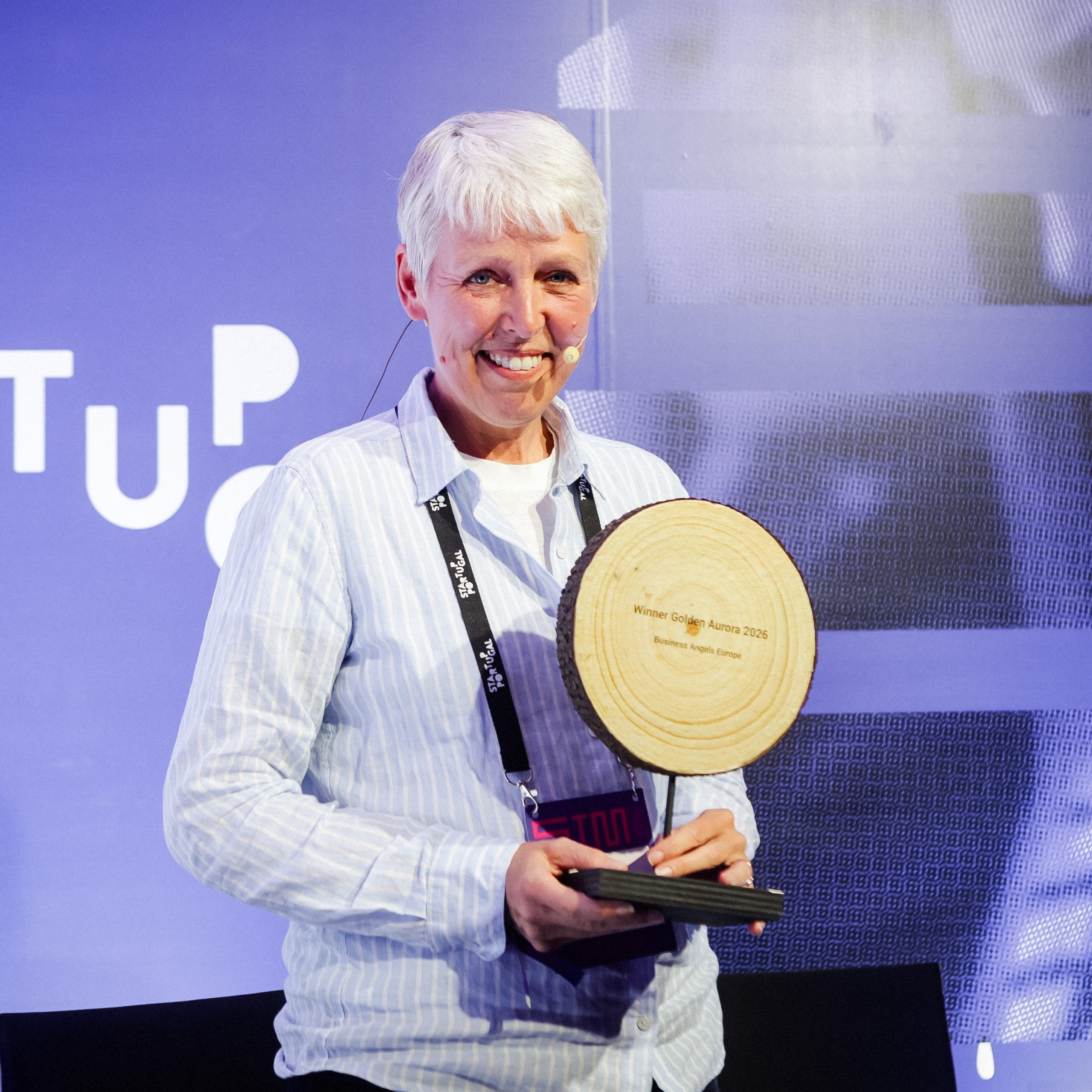 Vicky Brock standing on stage holding a wooden award.
